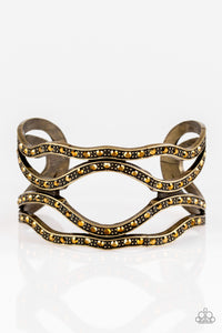 Speaks Volumes - Brass Item #P9ED-BRXX-033XX Encrusted in glittery aurum rhinestones, dotted brass bars wind across the wrist, coalescing into an edgy cuff.